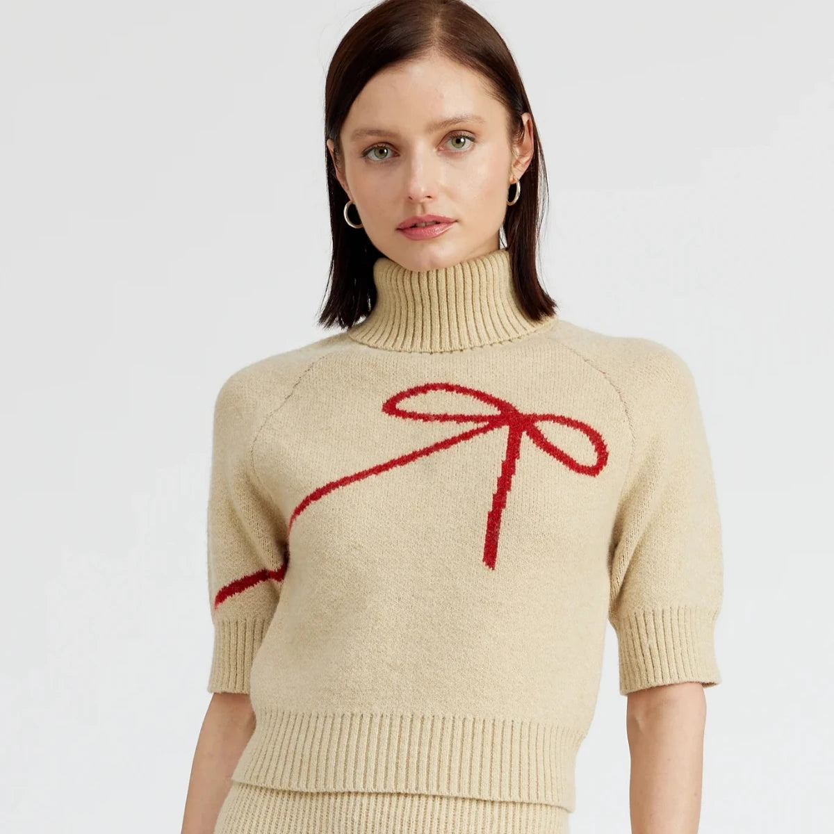 beige turtleneck sweater with short sleeves and red bow silhouette