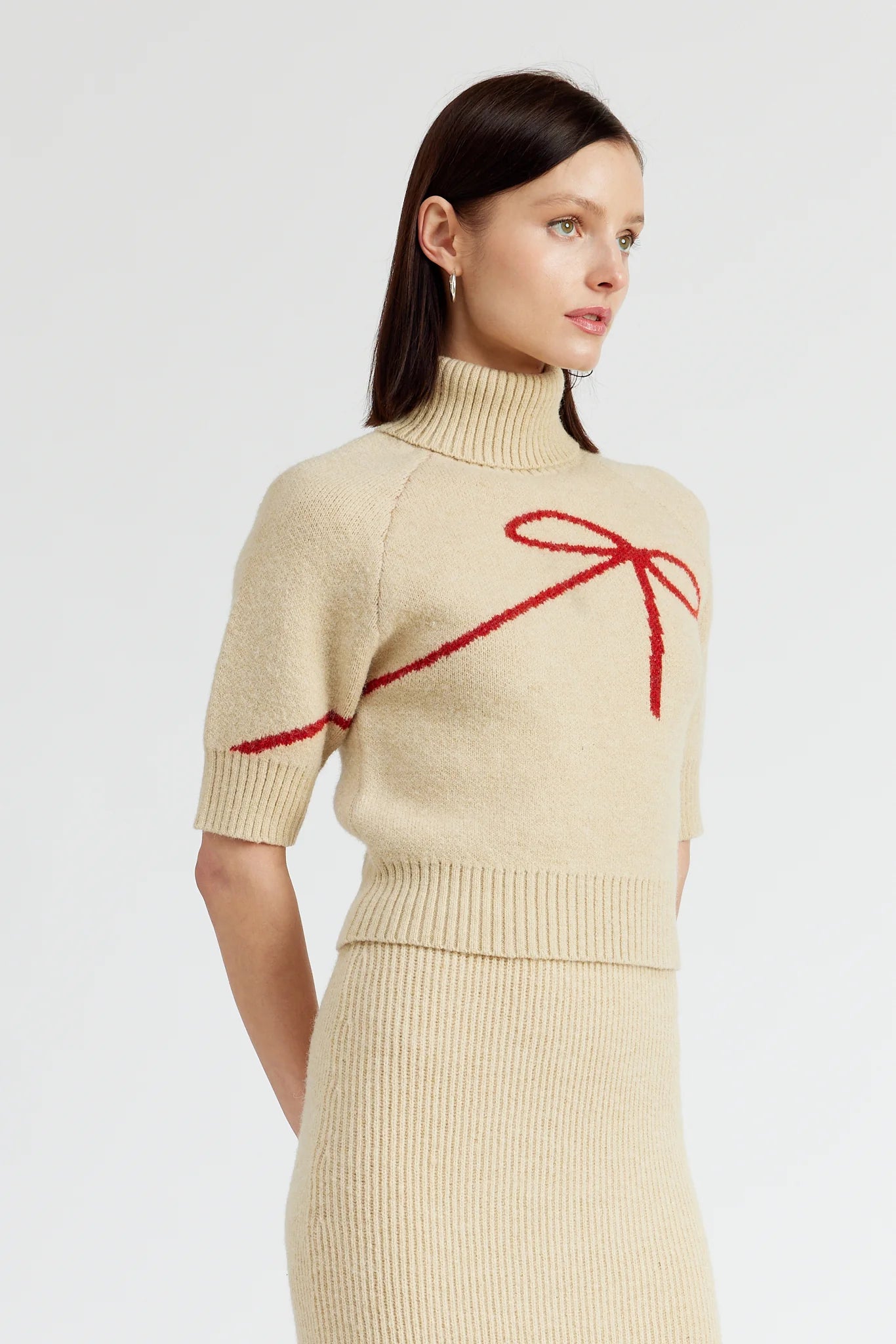 beige turtleneck sweater with short sleeves and red bow silhouette