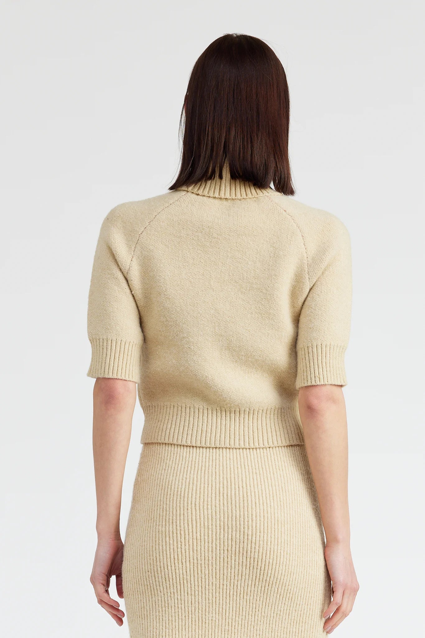 beige turtleneck sweater with short sleeves and red bow silhouette