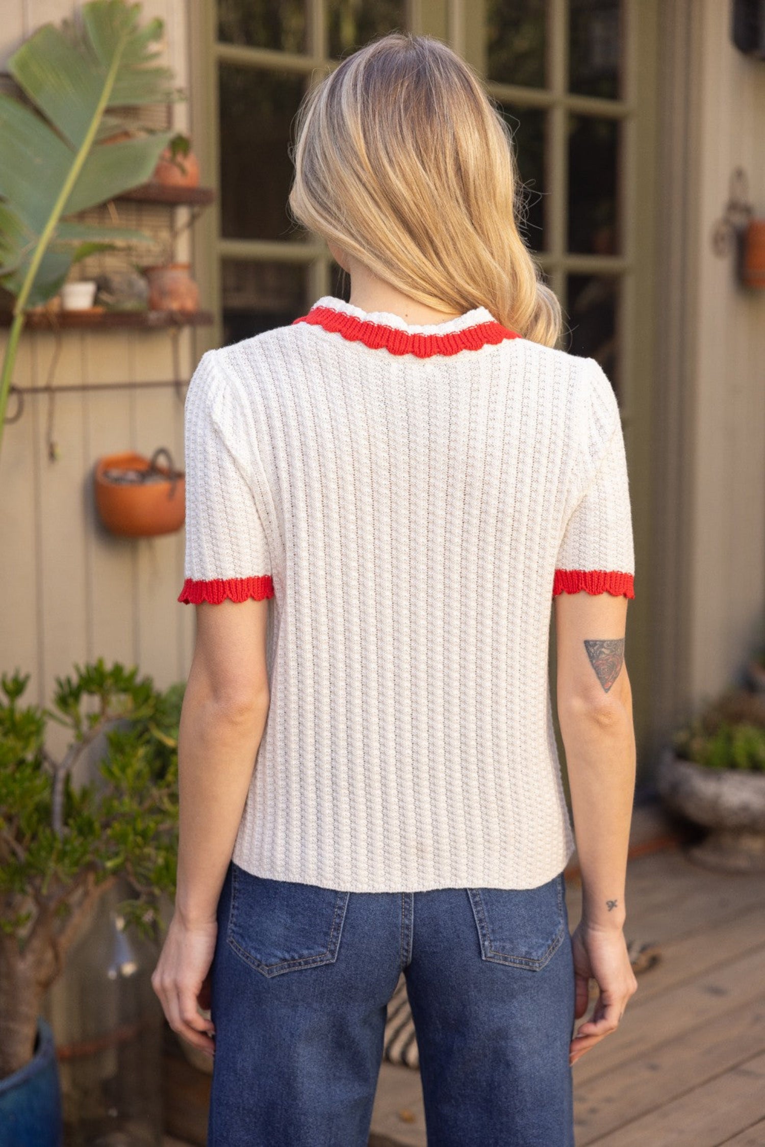 ivory knit short sleeve polo top with red trim, collar and pearl buttons