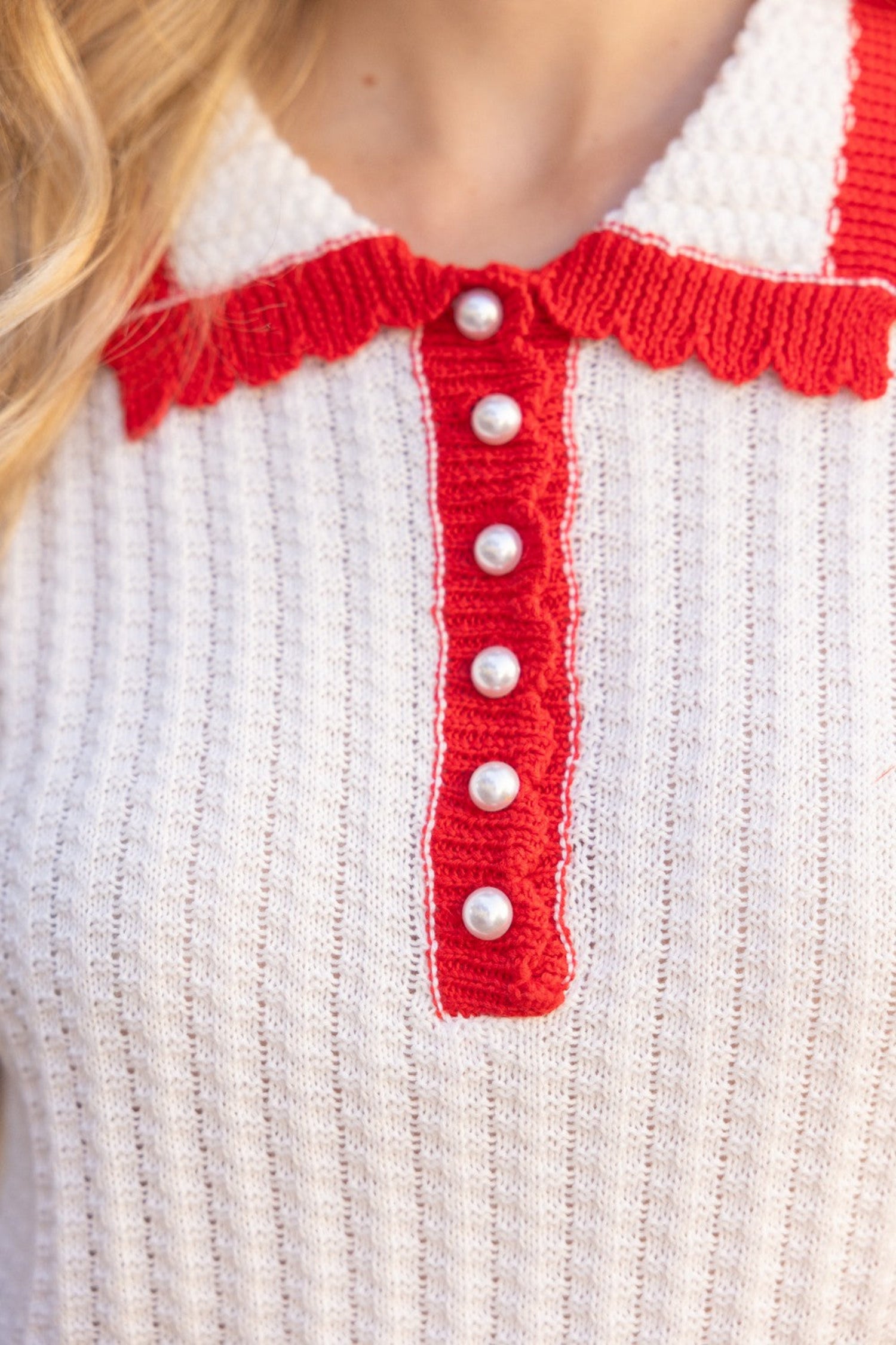 ivory knit short sleeve polo top with red trim, collar and pearl buttons