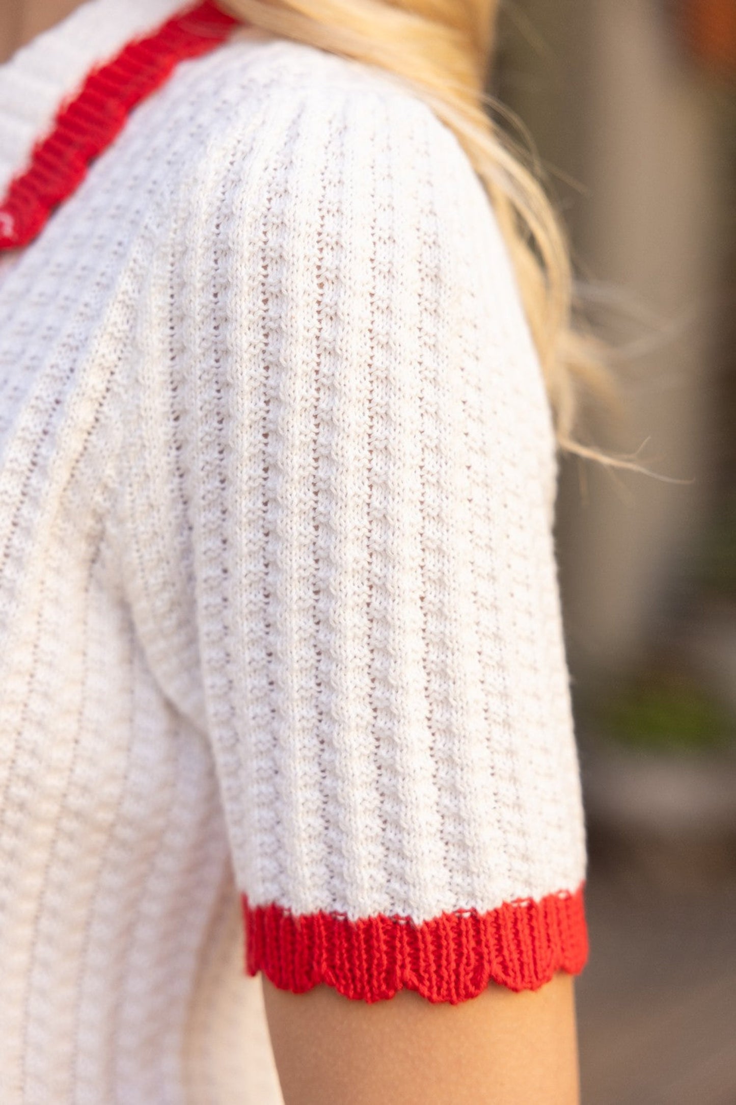 ivory knit short sleeve polo top with red trim, collar and pearl buttons